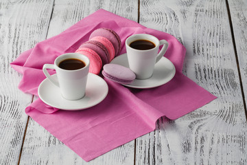 Two cup of espresso coffee with macaroons on pink background