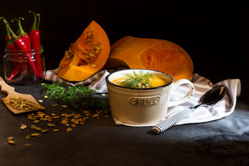 A bowl of cream soup with pumpkin on a black background, selective focus