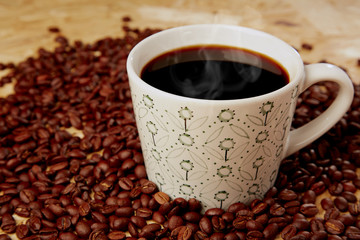 Hot coffee with beans on wooden texture