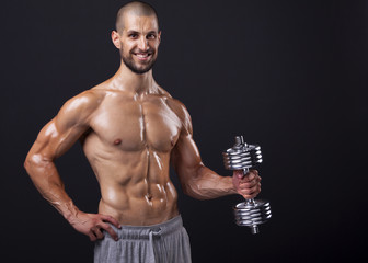 Fototapeta na wymiar Muscular man lifting weights over dark background