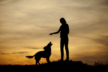Obraz na płótnie Canvas Silhouette of girl and her dog with beautiful sunset background.