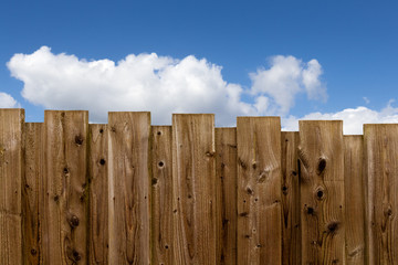 Holzzaun mit blauem Himmel und weißen Wolken