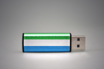 usb flash drive with the national flag of sierra leone on gray background.