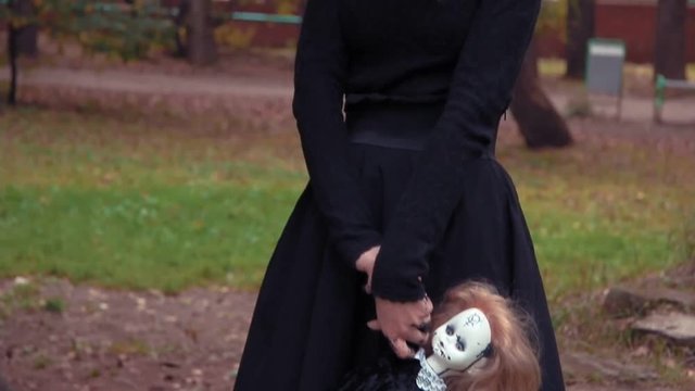 Photography shoot of a young woman in character of a scary white faced girl with a doll