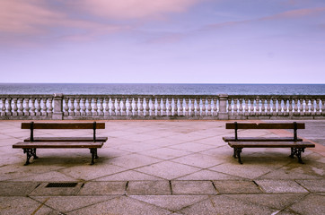 Fototapeta na wymiar Dos bancos con vistas en un paseo junto al mar