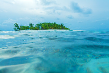 Small atoll island shot from water surface with some blurred dro - 120522042