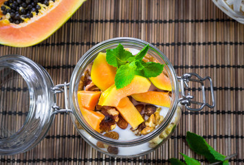 Healthy breakfast with exotic fruits, mint and yogurt on wooden tablecloth.