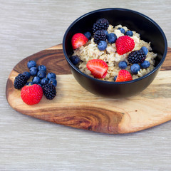 Oatmeal porridge in bowl topped with blueberries, blackberry, strawberries and mint. Healthy breakfast with vitamins