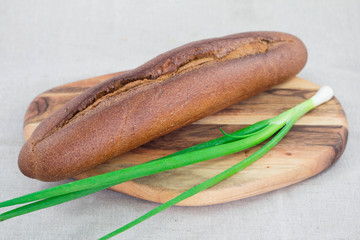 Brown bread and green onion on cutting board