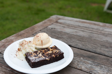 Brownie on white plate with ice cream