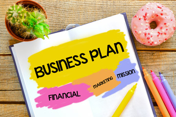 Naklejka premium Business plan written in the notebook on a wooden background