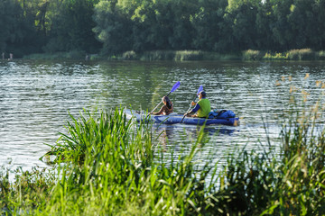 Fototapeta na wymiar man and woman rowing oars in the canoe on the river