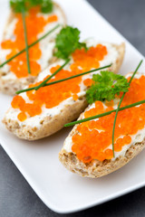 Red caviar on bread on white plate.