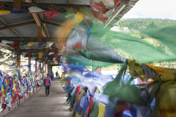 A group of people on a suspension bridge surrounded by Buddhist prayer flags.