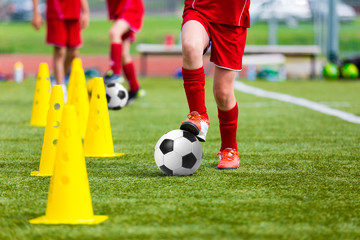 Soccer football players during the team training before the match. Exercises for football soccer youth team. Young player exercises with ball and marker cones