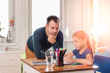 Father helping daughter to finish homework