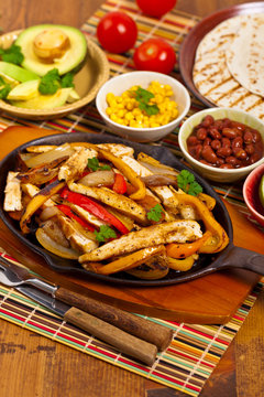 Chicken Fajitas with Grilled Onions and Bell Peppers serve with Tortillas. Selective focus.