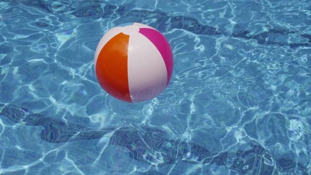 Colorful beach ball floating in pool