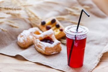 Fresh compote of dried fruits in plastic cups on rustic table with pasties. Selective focus