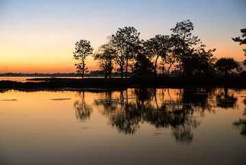 Obraz premium Beautiful sunset with reflection of big trees,Thailand.