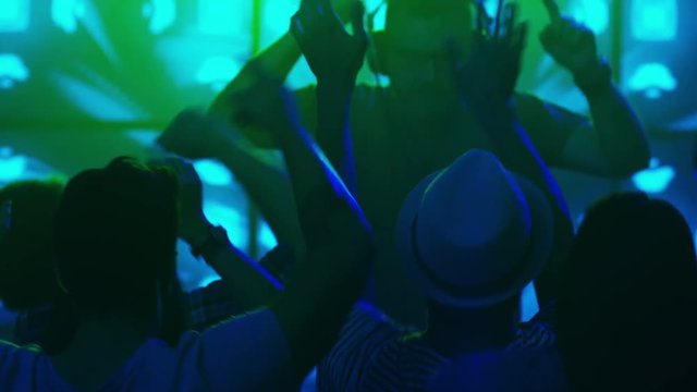 DJ Playing Music in Nightclub, People Dancing, Having Fun and Raising Hands