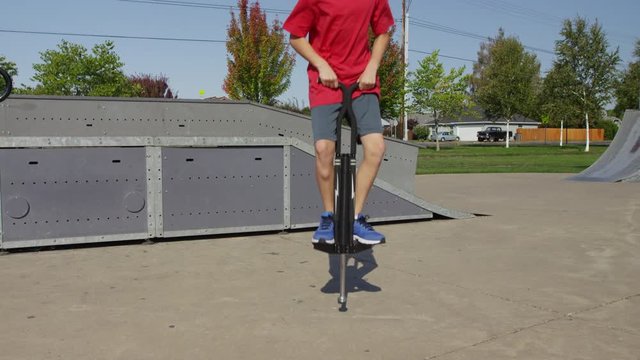 Boy jumping on Pogo stick at park