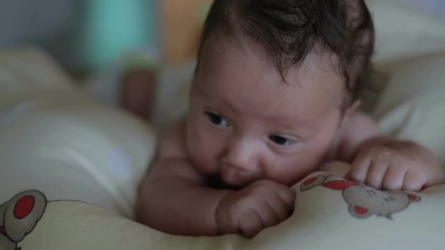 Baby infant is try raises head, lying at the bed
