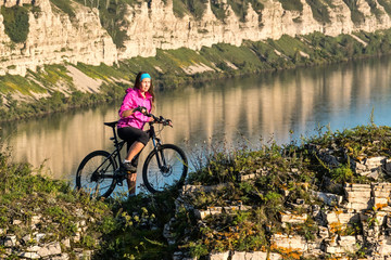 Young woman standing on the top of cliff with bicycle