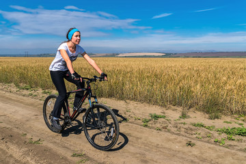 Fototapeta premium girl rides bicycle on the road in a field