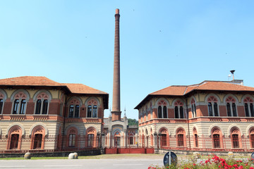 Fototapeta na wymiar Factory with chimney at historic industrial town Crespi d'Adda near Bergamo, Lombardy, Italy