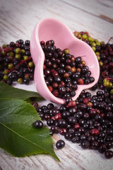 Fresh elderberry with leaf in glass dish on old wooden background