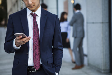 Businessman, looking at a smart phone in the office district