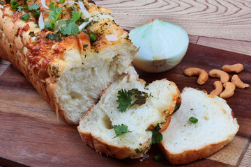 Homemade spinach bread with halves onion and cashew nuts on butcher served. Side view.