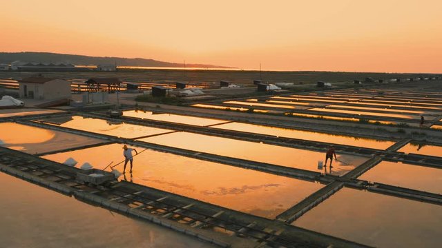 Aerial, tracking shot of salt pans workers sunset
