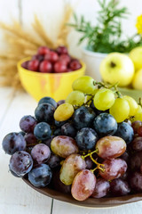 Freshly picked grapes in several varieties of clay bowl on a light background.