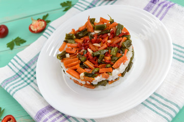 Rice and fried vegetables (asparagus beans, carrots) - vegan diet garnish. Decorated layers of salad on a white plate.