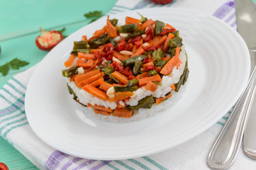 Rice and fried vegetables (asparagus beans, carrots) - vegan diet garnish. Decorated layers of salad on a white plate.