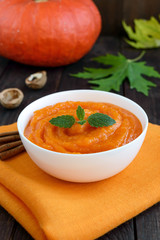 Organic pumpkin puree (soup) in a white bowl on dark wooden background. Dietary dish. Baby food