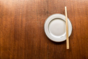 chopsticks with white dish on wood table with copy space.