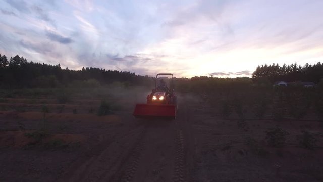 Farmer mowing dusty crops on tractor