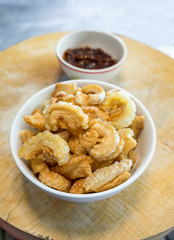 Pork snack, pork rind in bowl with thai chili sauce on wood block