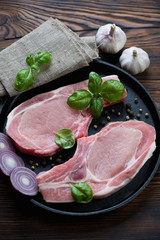 Frying pan with fresh uncooked pork loin cutlets on bone