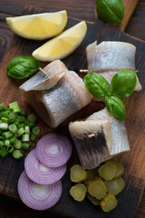 Herring fillet rolls with onion, gherkins and lemon, close-up