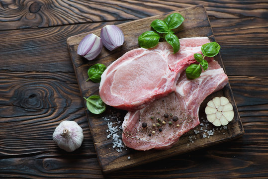 Raw seasoned pork meat steaks, rustic wooden setting, above view