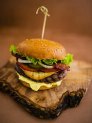 Tasty street food grilled beef burger in crispy shortbread with lettuce and mayonnaise served on small cutting board.