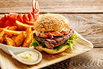 Hamburger filled with bacon and beef with fries