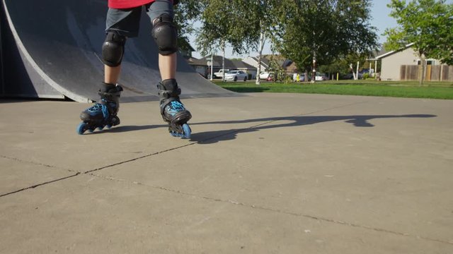 Boy Rollerblading at park, closeup of feet