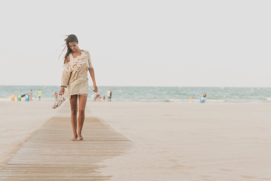 Barefoot pretty woman walking along beach
