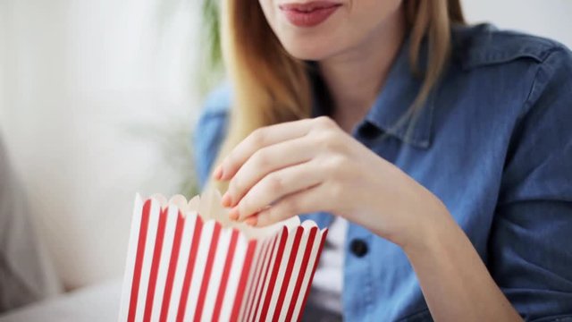 happy woman eating popcorn and watching tv at home