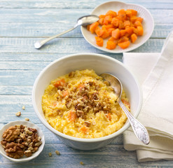 Corn porridge with pumpkin, honey and walnuts on a blue wooden background